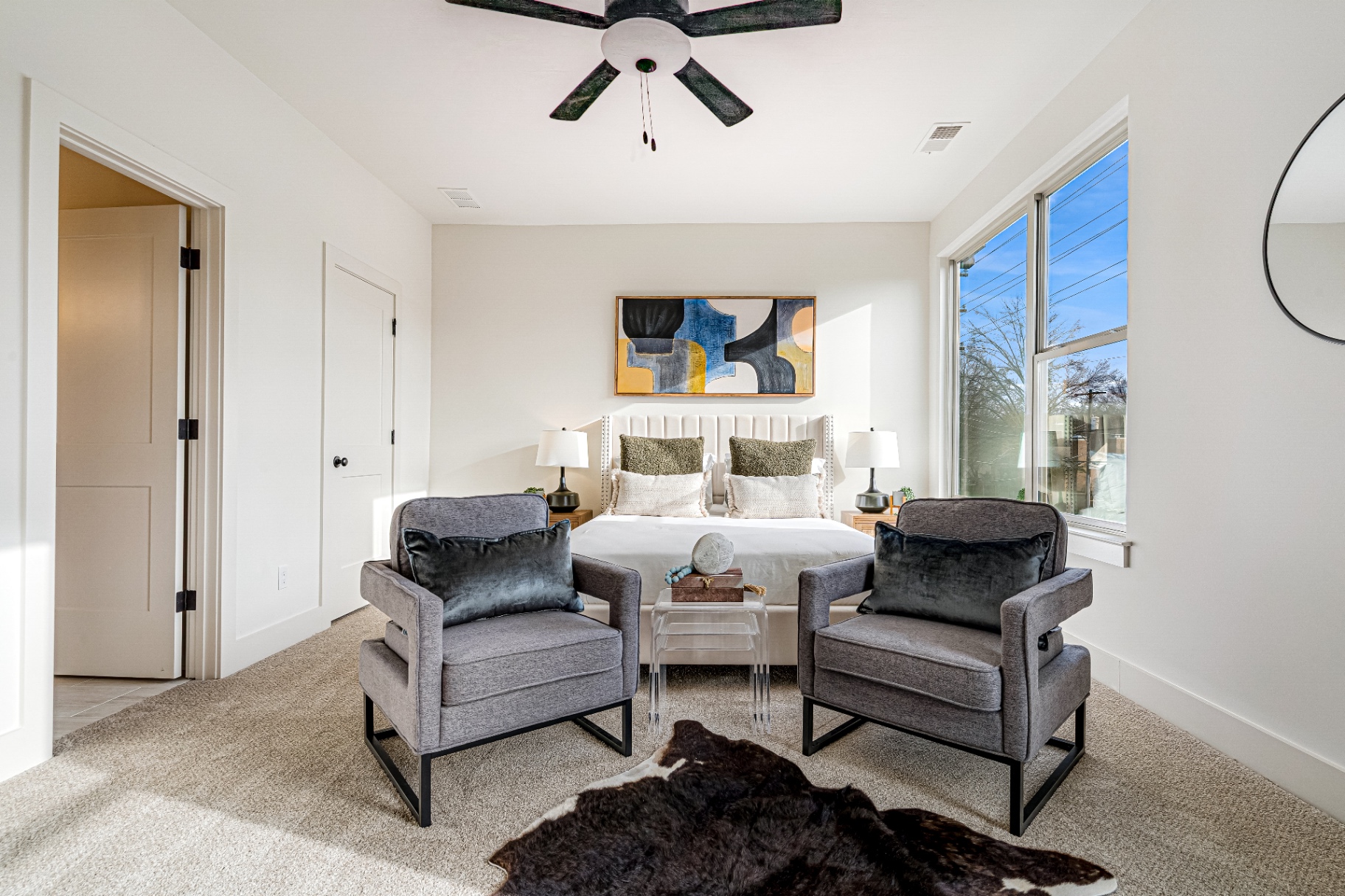 Primary suite with king bed, lounge chairs, and floor-to-ceiling windows
